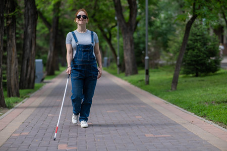Blind pregnant woman walking in the park with a cane.の写真素材
