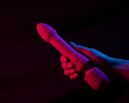 Woman holding a vibrator in neon pink and blue light.の写真素材