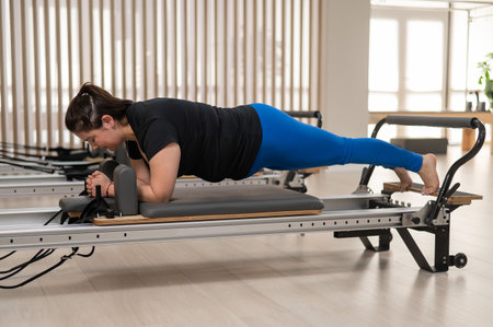 Overweight caucasian woman doing pilates exercises on a reformer.