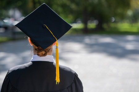 A woman throws her graduation cap against the blue sky.の写真素材