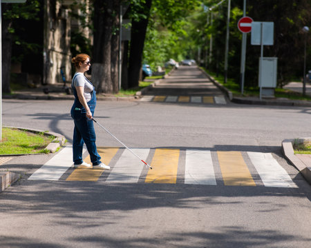 Blind pregnant woman crosses the road at a crosswalk with a cane.の写真素材