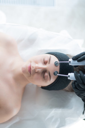 Young caucasian woman on microcurrent therapy procedure. Beauticians office.の写真素材