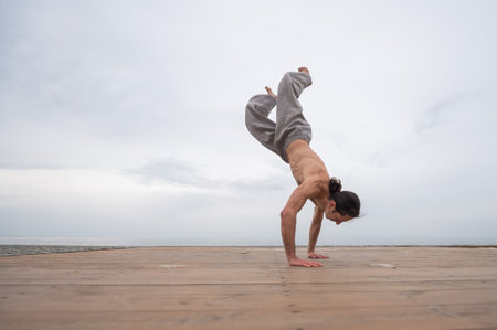 Caucasian man with naked torso practicing wushu on the seashore.