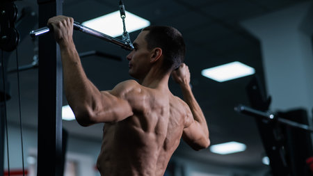 A man does a chest pulldown in the gym.