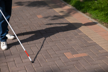 A faceless blind woman walks down the street with a cane.の写真素材