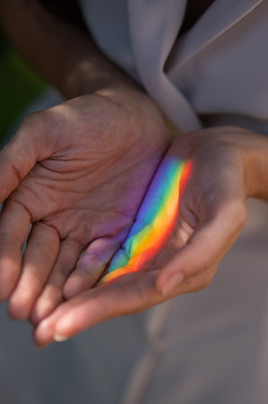 Faceless woman catching rainbow ray with her hands outdoors.の写真素材