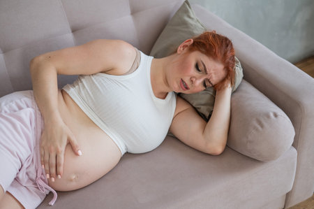 Caucasian pregnant woman lies on the couch and suffers from pain.の写真素材