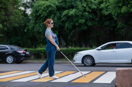 Blind pregnant woman crosses the road at a crosswalk with a cane.の写真素材