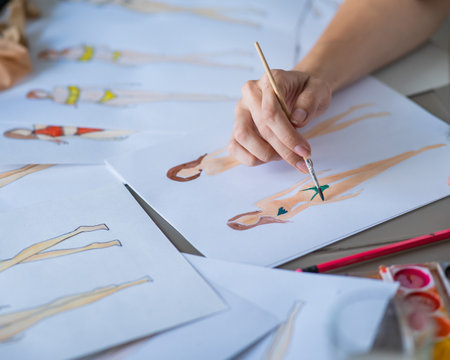 Faceless woman draws sketches of swimwear. Close-up of the hands of a fashion designer.の写真素材