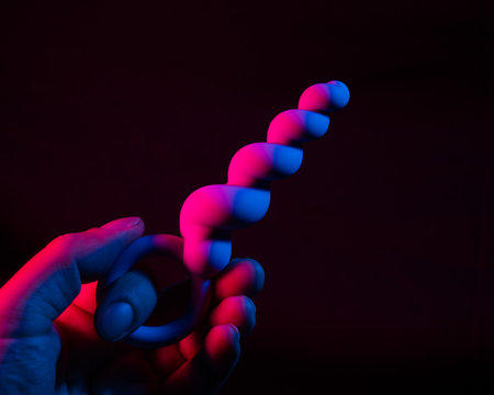 Woman holding anal beads in neon pink blue light.の写真素材