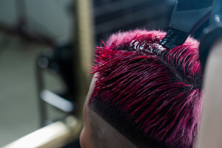 Close-up of the process. The hairdresser dyes the hair of an Asian woman in pink. Short extreme haircut.の写真素材