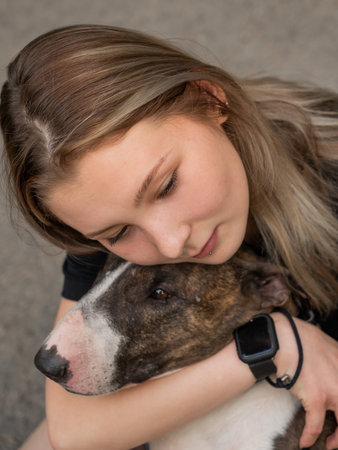 Portrait of caucasian woman hugging her bull terrier dog outdoors.の写真素材