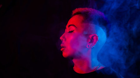 Profile Asian woman with short haircut smoking in neon light.の写真素材