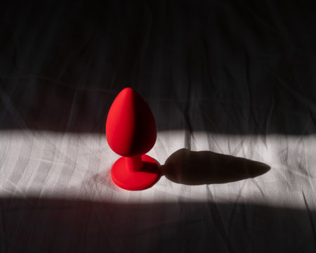 Red silicone anal plug on a white sheet.の写真素材