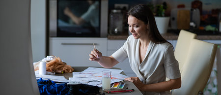 Woman drawing sketches of swimwear and underwear in watercolor while sitting in the kitchen.