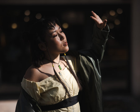 Portrait of a young Asian woman in a green leather coat on a walk. Girl enjoying the sun.の写真素材