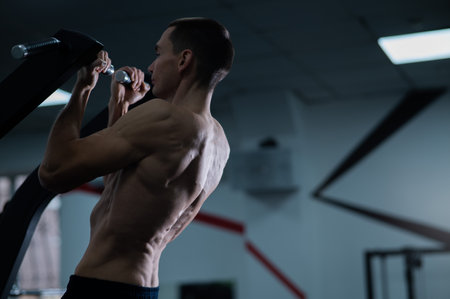 Back view of shirtless man with pull-ups in gym. Narrow grip.