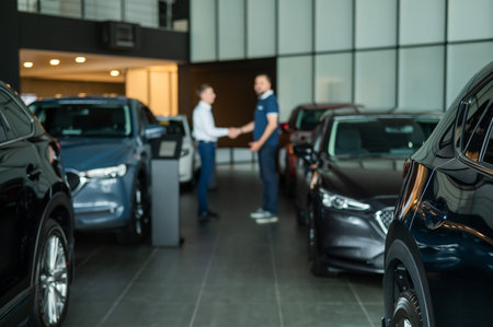 Seller and buyer shake hands in a car dealership. Caucasian man buys a car.の写真素材