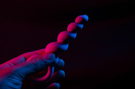 Woman holding anal beads in neon pink blue light.の写真素材