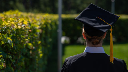 A woman throws her graduation cap against the blue sky.の写真素材