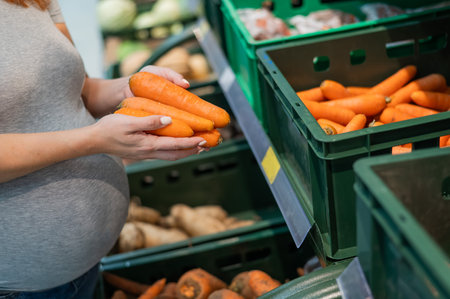Pregnant woman buys carrots in the store.の写真素材