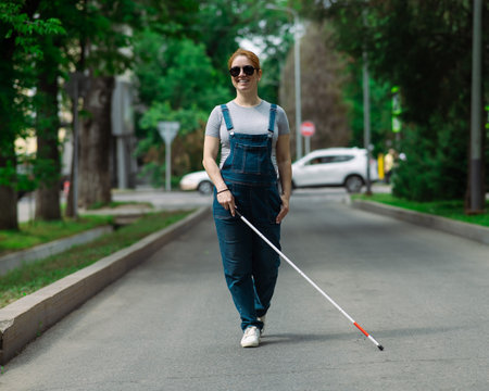 Blind pregnant woman walking down the street with a cane.の写真素材