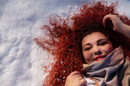 Top view of a fat red-haired woman lying on the snow