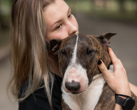 Portrait of caucasian woman hugging her bull terrier dog outdoors