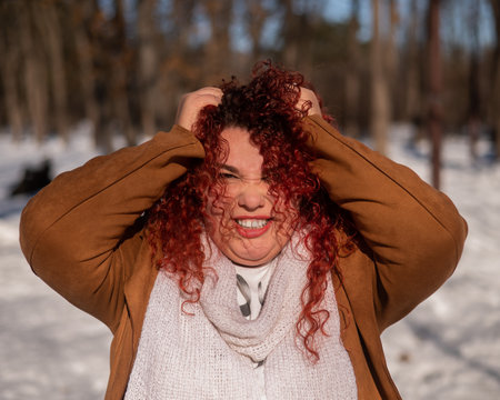 Portrait of a grimacing plump red-haired woman on a walk in winterの写真素材