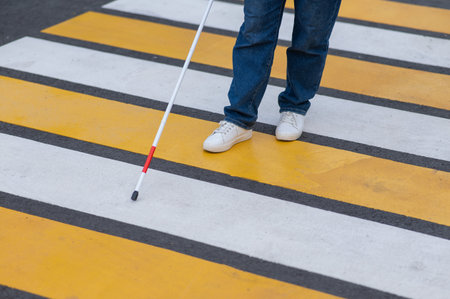 Close-up of the legs of a blind woman crossing the road at a crosswalk with a caneの写真素材