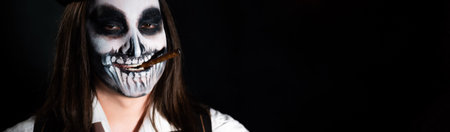 Young man wearing skull makeup in the dark. Halloween skeleton costume.