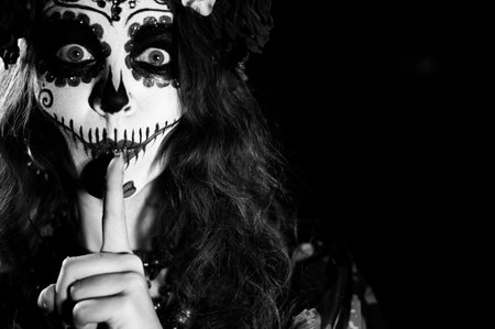 Woman in santa muerte makeup on a black background. Girl wearing traditional mexican holy death...
