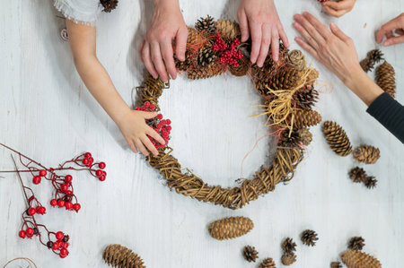 DIY Christmas crafts with the whole family. Handmade wreath. Hands of mothers grandmother and two granddaughters.の写真素材