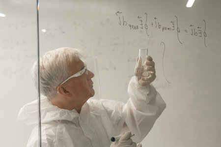 An elderly Caucasian male chemist in a protective suit writes on glassの写真素材