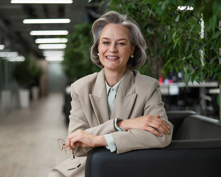 Attractive mature woman sitting on sofa in lobbyの写真素材