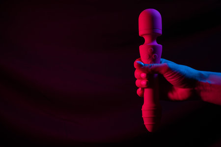 Woman holding a vibrator in neon pink and blue light