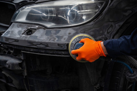 A mechanic sands the putty on a car body with a machine. Repair after an accidentの写真素材