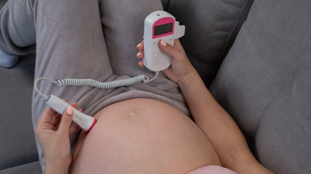 Close-up of a pregnant womans belly using a home doppler. Blank screen