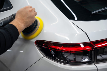Process of polishing white car body surface using orbital polishing machineの写真素材