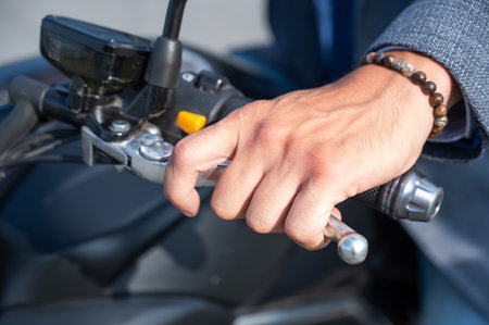 Caucasian man rides an electric motorcycle. Close-up of a mans hand pressing the brake on the steering wheelの写真素材
