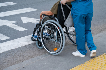 Rear view of a nurse helping an elderly woman in a wheelchair cross the road