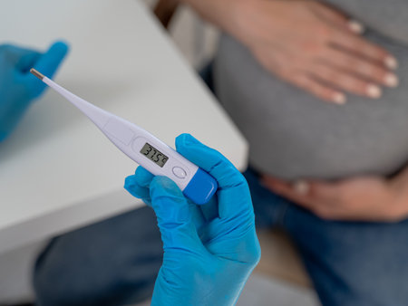 Pregnant woman with fever at doctors appointment. Therapist holds an electronic thermometer with a temperature of 37.5の写真素材