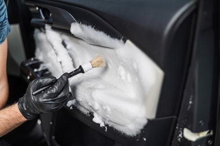 A man cleans the interior of a car with foam and a brush. Clean the door trimの写真素材
