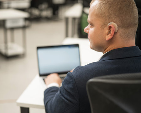Caucasian deaf man typing on laptop in officeの写真素材