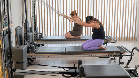 Two pregnant women do Pilates exercises on a reformerの写真素材
