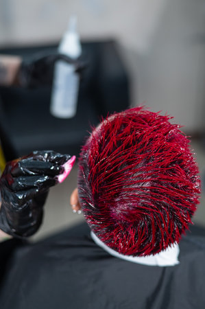 The hairdresser removes excess dye from the skin of a female with a cotton pad.Asian woman with a short haircut in a hairdressing salonの写真素材