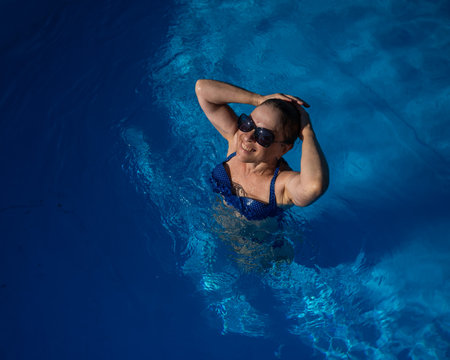 An elderly woman in sunglasses swims in the pool. Vacation in retirementの写真素材