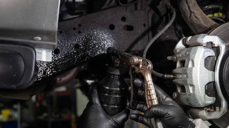 An auto mechanic applies anti-corrosion mastic to the underbody of a carの写真素材