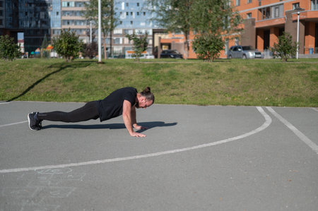 Bearded man with long hair doing push-ups on the sports ground