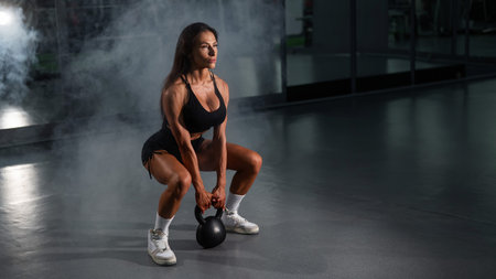 Caucasian woman squats with kettlebell in the gymの写真素材